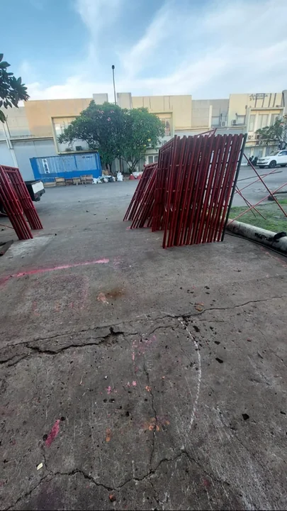 Frame scaffolding merah ditumpuk di lahan terbuka dekat bangunan